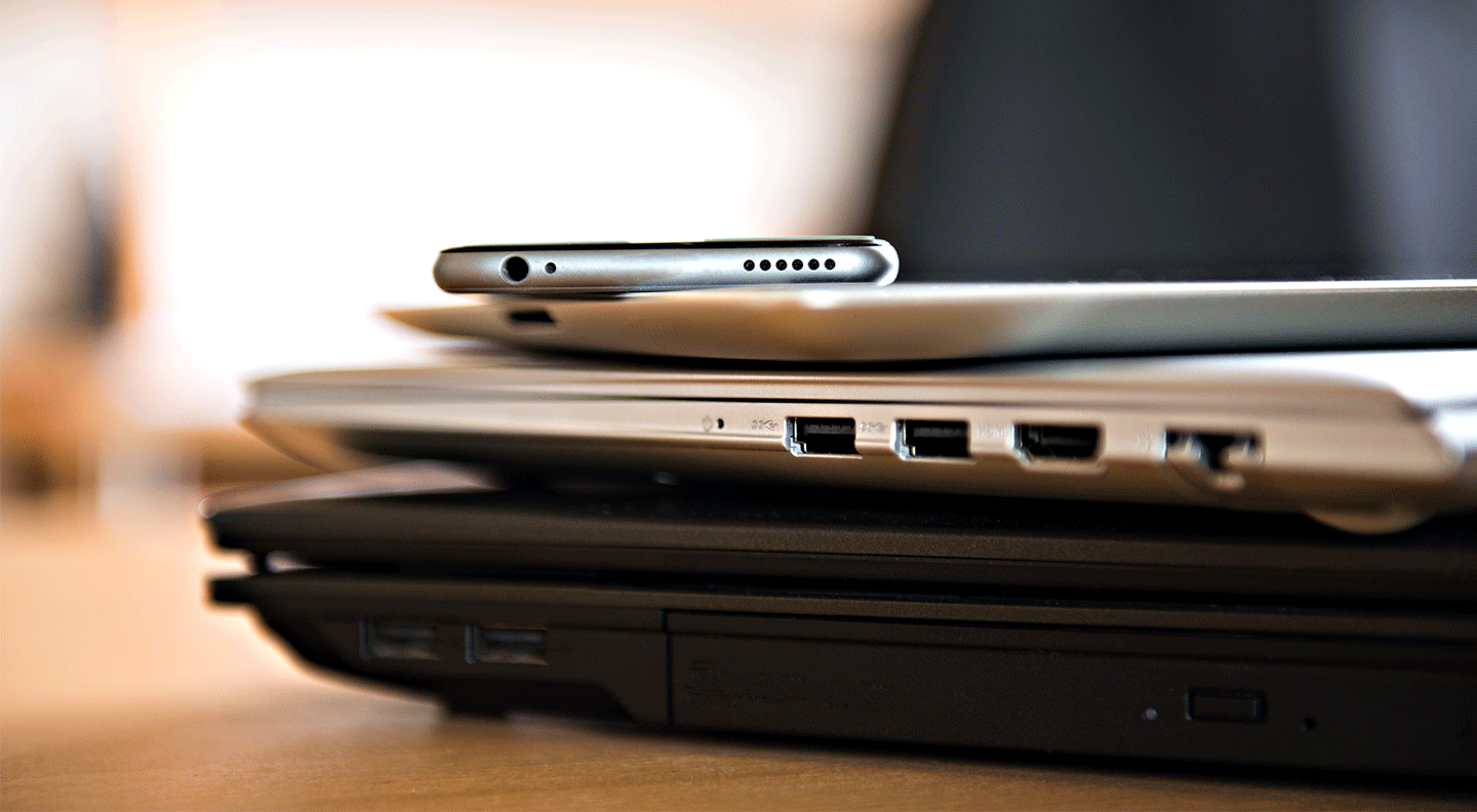 pile of different computers and phone on table