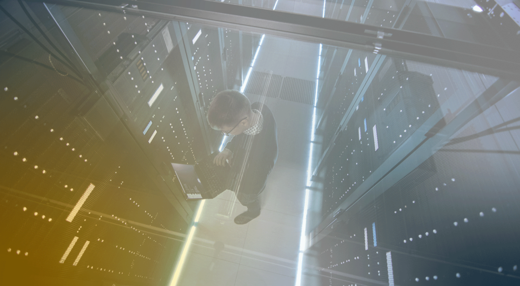 man looking at laptop in a data center