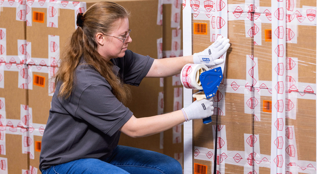 Female employee securing boxes using tape gun
